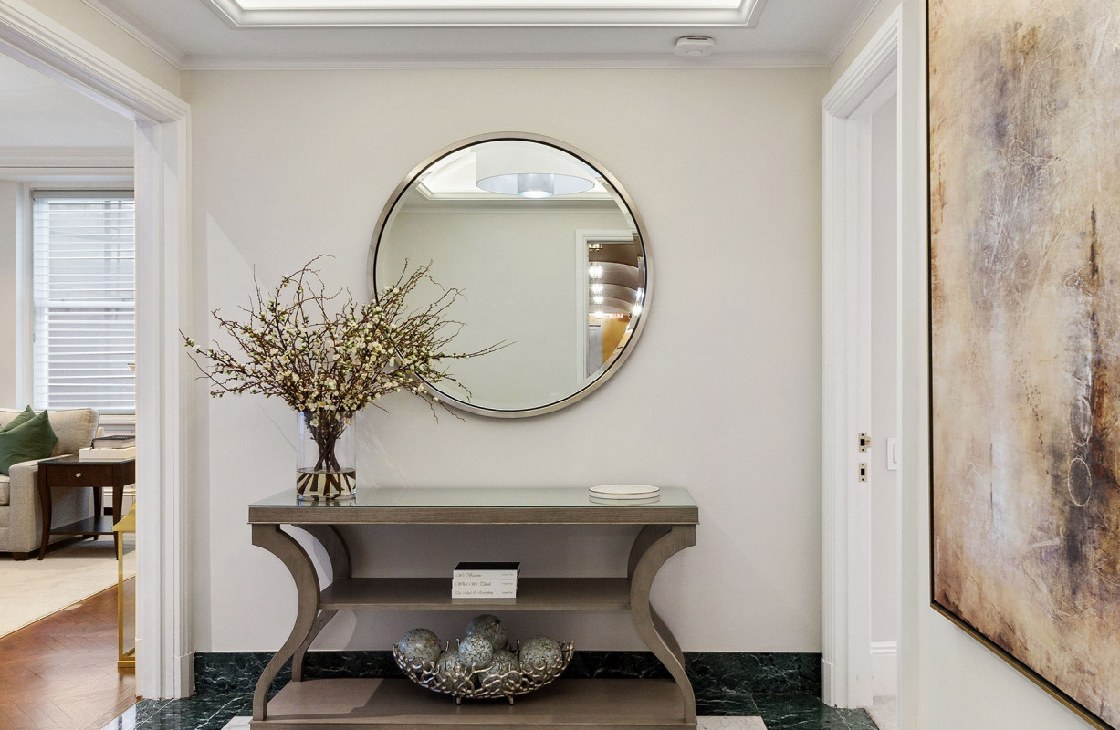 Elegant entryway at The Sherry-Netherland with a round mirror, floral arrangement, and modern console table