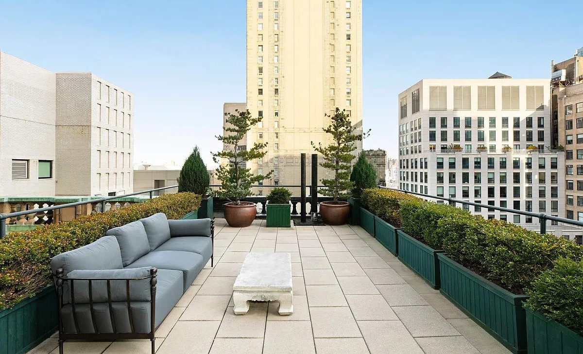 An elegant rooftop terrace at The Sherry-Netherland with comfortable outdoor seating, manicured greenery, and views of the surrounding New York City skyline.